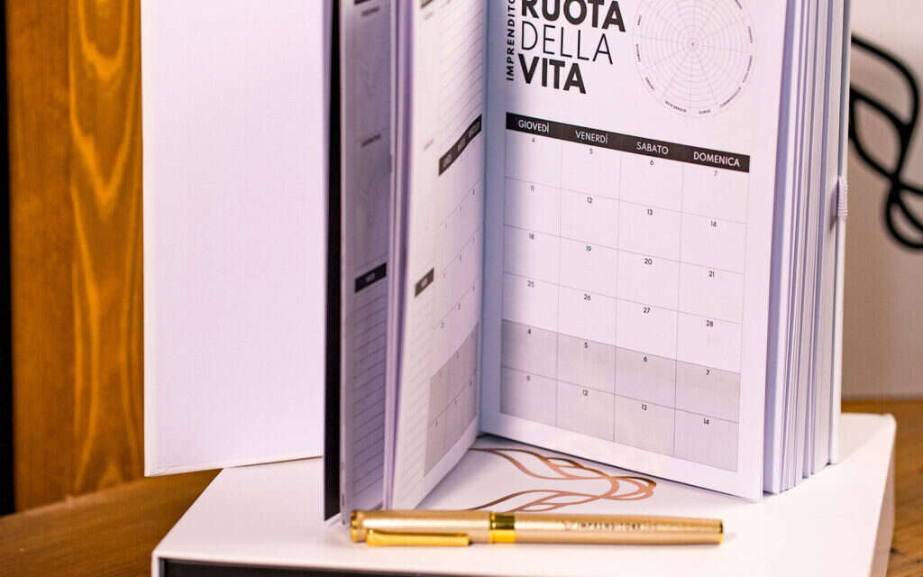 Goal Planner aperto sulla pagina della Ruota della Vita, con penna dorata
